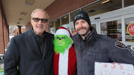 Supervisor Mike McCready and BTPD Sgt Soley with the Grinch dressed like Santa outside of a grocery store entrance.