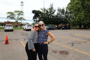 Two ladies with their arms around each other in a parking lot