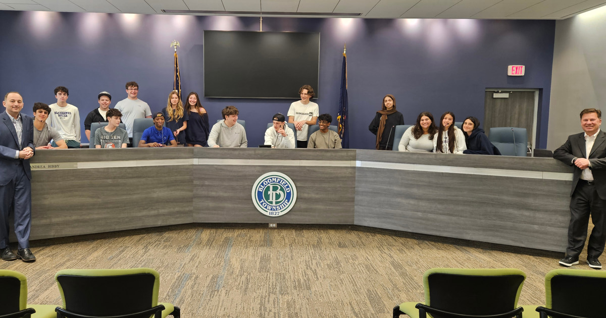 High School Civics Class students gathered behind the dais in the Bloomfield Township Hall Auditorium with Treasurer Schostak and Clerk Brook on either side