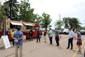 A line of people waiting to order from a taco food truck